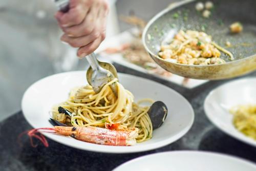 a person eating pasta on a plate with a fork at Residence Duna Rossa - Family Friendly in Duna Verde
