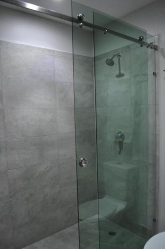 a shower with a glass door and a sink at AMD Hotel in San Juan de los Lagos