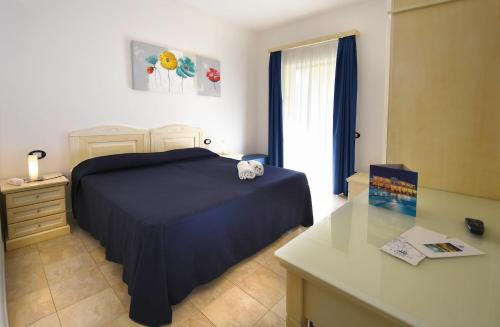a bedroom with a bed and a desk and a window at Hotel Ristorante Il Vascello in Costa Rei