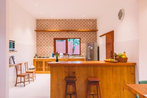 a kitchen with a wooden bar with stools in it at Casa Crescente in Trancoso