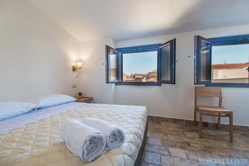 a bedroom with a bed and a chair and two windows at Karama in Dorgali
