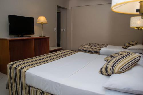 a hotel room with two beds and a television at Marcopolo Suites Iguazu in Puerto Iguazú
