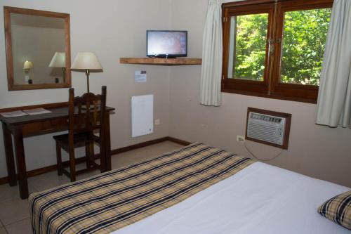 a bedroom with a bed and a desk and a television at Marcopolo Suites Iguazu in Puerto Iguazú