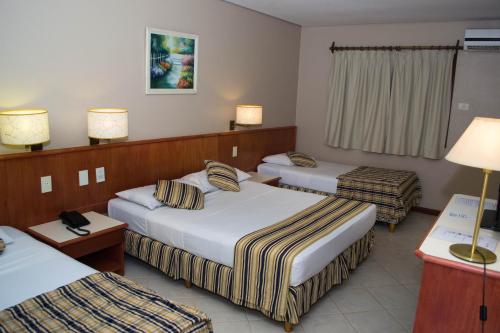 a hotel room with three beds and two lamps at Marcopolo Suites Iguazu in Puerto Iguazú