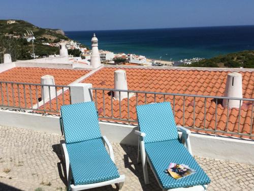 two blue chairs sitting on a balcony overlooking the ocean at DOCEVIDA Appartement # Ocean View in Salema