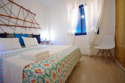 タリファにあるLivingtarifa Lances Blueのベッドルーム1室(ベッド1台、椅子、窓付)