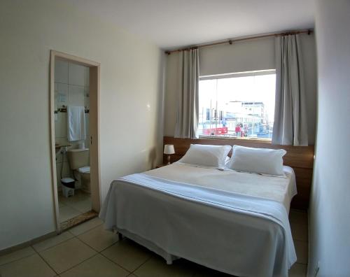 a bedroom with a large bed and a window at Hotel Monte Carlo in São João del Rei