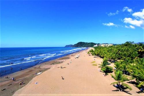 a beach with a lot of people and the ocean at Beach Break Resort & CR Surf Camp in Jacó