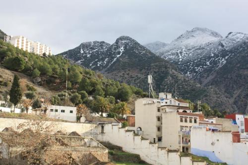 une ville avec des montagnes enneigées en arrière-plan dans l'établissement Dar Al Machichi, à Chefchaouen