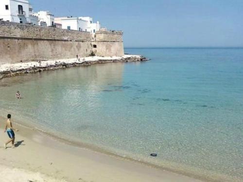 a man walking on a beach next to the ocean at Palazzo Kapece in Monopoli