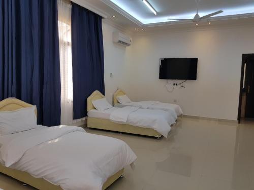 a room with three beds and a flat screen tv at Alarbee Aljeded in Salalah