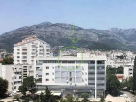 a large white building in front of a mountain at Апартаменты Ирина М in Bar