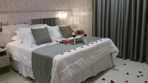 a bedroom with a large white bed with red roses on it at Valérius Palace Hotel in Ariquemes