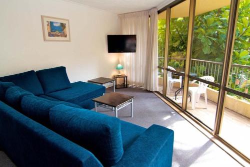 a living room with a blue couch and a balcony at Enderley Gardens Resort in Gold Coast