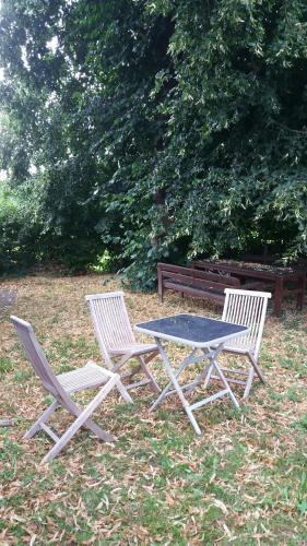 2 weiße Stühle, ein Tisch und eine Bank in der Unterkunft Ferienwohnung Biermann in Aspach
