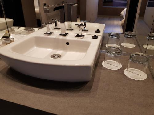 a white sink and two glasses on a counter at Garden Plaza in San Miguel de Tucumán