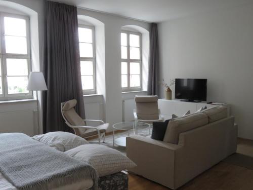 ein Schlafzimmer mit einem Sofa und Stühlen sowie einem TV in der Unterkunft Historisches Bürgerhaus Dresden -Kulturstiftung- in Dresden