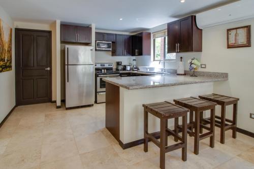 a kitchen with a refrigerator and a counter with stools at The Cove 9/10 in Ocotal