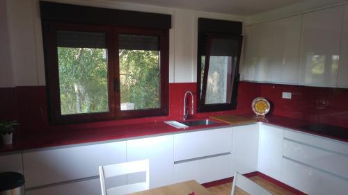 a kitchen with red and white cabinets and windows at Casa A Veiga in O Grove