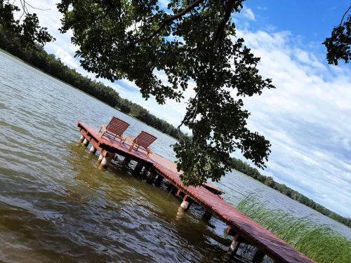 two benches sitting on a dock in the water at Dwa Pomosty in Augustów
