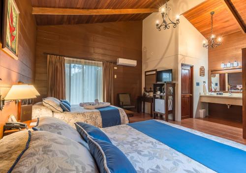 a hotel room with two beds and a bathroom at Hotel El Silencio del Campo in Fortuna
