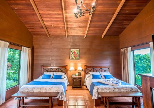 two beds in a room with wooden walls and windows at Hotel El Silencio del Campo in Fortuna
