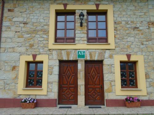 ein Steingebäude mit braunen Türen und Fenstern in der Unterkunft Apartamentos Rurales El Gobernador in Villaviciosa