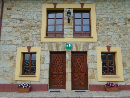 un edificio de piedra con puertas y ventanas marrones en Apartamentos Rurales El Gobernador, en Villaviciosa
