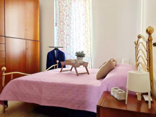 1 dormitorio con 1 cama rosa, vestidor y ventana en Carpenino's home en La Spezia