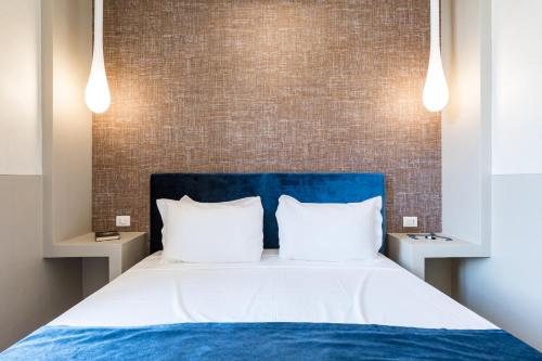 a bed with a blue headboard and two white pillows at A World Aparts - Barberini Boutique Hotel in Rome