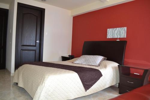 a bedroom with a bed and a red wall at Hotel Victoria in Chinchiná