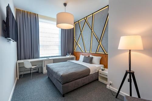 a bedroom with a bed and a desk and a window at Park Hotel Bydgoszcz in Bydgoszcz
