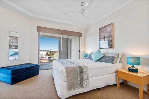 a bedroom with a large white bed and a window at Rovera Apartments in Maroochydore