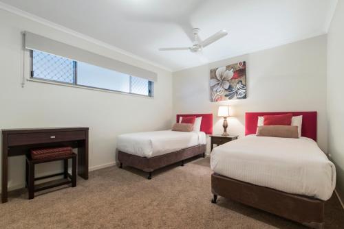 a bedroom with two beds and a desk and a window at Rovera Apartments in Maroochydore
