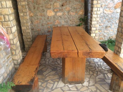 a wooden table with two benches next to a stone wall at Apartman Nadia in Karlobag