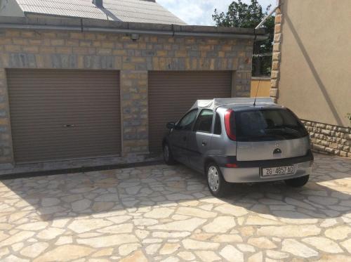 a small car parked in front of a garage at Apartman Nadia in Karlobag