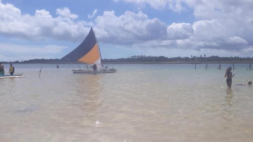 a sail boat in the water with people on a beach at Recanto Vendramel Bezerra in Jijoca de Jericoacoara