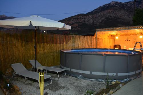 a hot tub with two chairs and an umbrella at Elias Maro House in Avdou