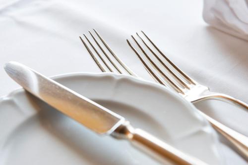 a white plate with a knife and fork on a table at Gasthof Kreuz Mühledorf in Mühledorf