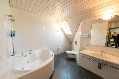 ein Badezimmer mit einer Badewanne, einem Waschbecken und einem WC in der Unterkunft Gasthof Kreuz Mühledorf in Mühledorf