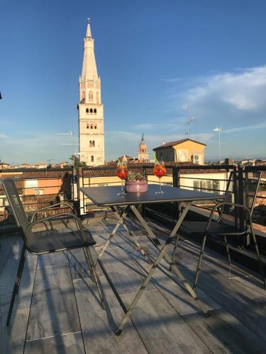 a table and chairs on a roof with a clock tower at Modena Charme in Modena