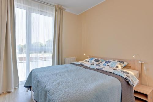 a bedroom with a bed and a large window at INA Rent - Tre Mare Apartamenty in Gdańsk