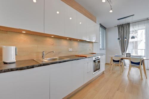a white kitchen with a sink and a table at INA Rent - Tre Mare Apartamenty in Gdańsk