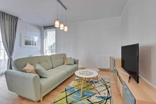 a living room with a couch and a tv at INA Rent - Tre Mare Apartamenty in Gdańsk