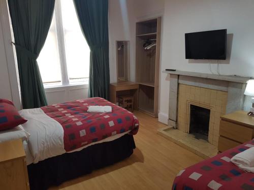 a hotel room with two beds and a fireplace at Bentinck Street Ground Floor Apartment in Glasgow