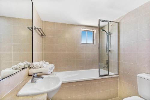 a bathroom with a sink and a bath tub at Rovera Apartments in Maroochydore