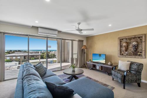 a living room with a blue couch and a tv at Rovera Apartments in Maroochydore