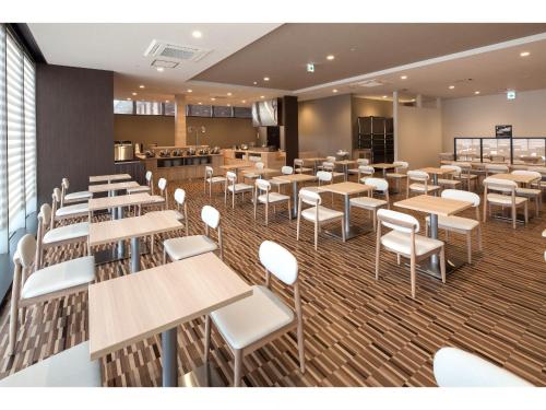 a dining room with tables and white chairs at Y's Hotel Asahikawa Ekimae in Asahikawa