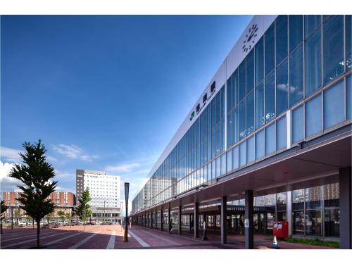 a large glass building with a tree in front of it at Y's Hotel Asahikawa Ekimae in Asahikawa