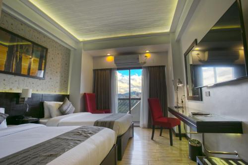 a hotel room with two beds and a window at Venus Parkview Hotel in Baguio